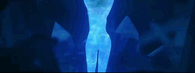 a statue of a woman is surrounded by glowing blue crystals in a dark room .