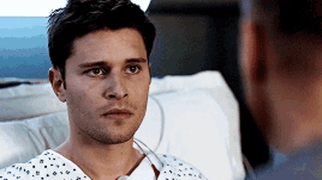 a man in a hospital gown is talking to another man .