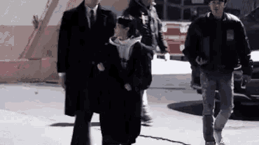 a man in a suit and tie is walking down the street with a woman in a black coat .