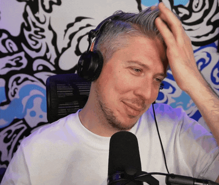 a man wearing headphones holds his hand to his head in front of a microphone