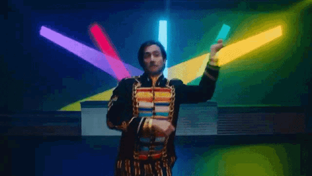 a man in a colorful jacket is dancing in front of a bunch of lights .