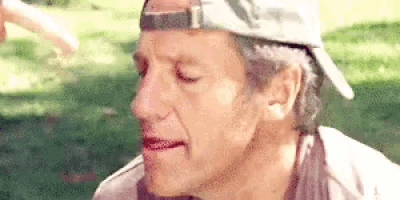 a close up of a man wearing a baseball cap and making a funny face .