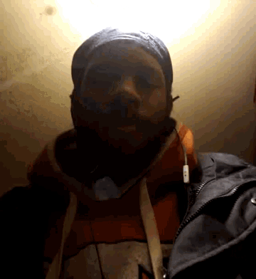 a man with a beard wearing a hat and earbuds