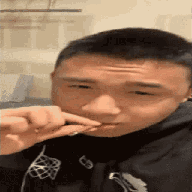 a young man is brushing his teeth with a toothbrush and making a funny face .
