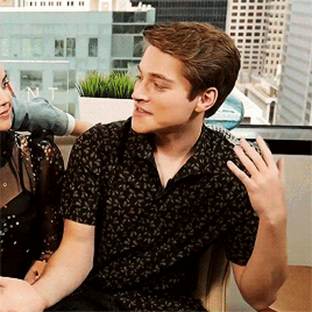 a man and a woman are sitting next to each other and the man is wearing a black shirt