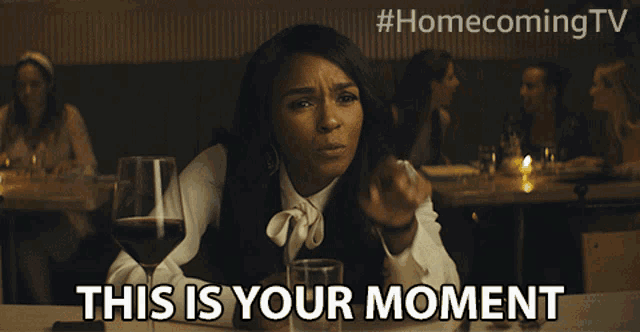 a woman sits at a table with a glass of wine and the words " this is your moment "
