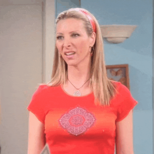 a woman wearing a red shirt with a necklace and a headband is smiling
