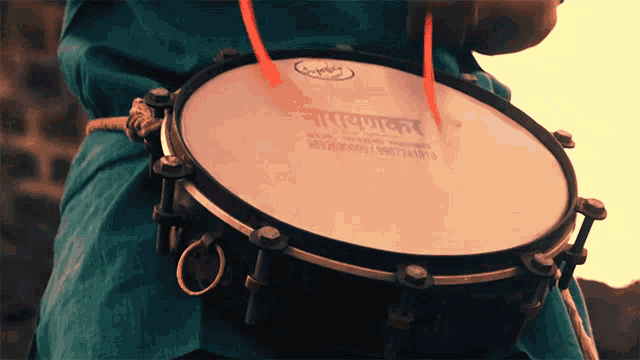 a person is playing a drum with a sticker on it that says ' nmvpnakar ' on it