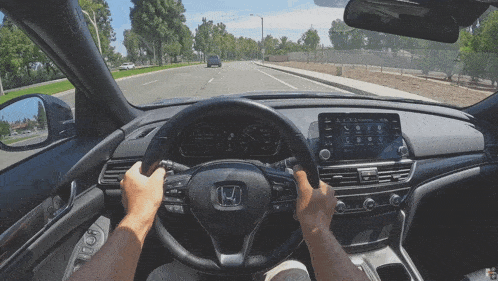 a man is driving a honda with a steering wheel that says h on it