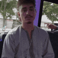 a man with a beard is sitting in the back seat of a car and looking at the camera .