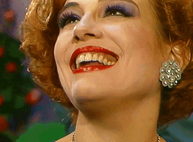 a woman with red lips and earrings is smiling
