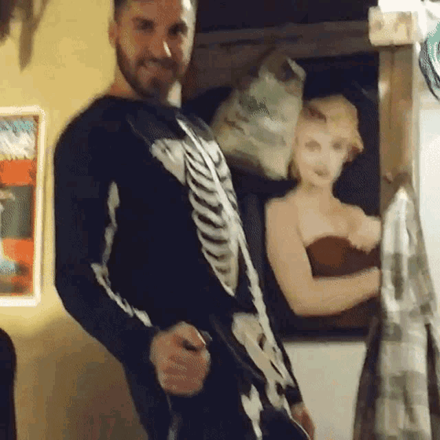 a man in a skeleton costume is standing in front of a painting of marilyn monroe