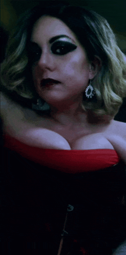 a woman wearing a red top and black earrings