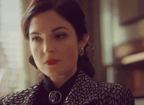 a close up of a woman 's face with a brooch around her neck