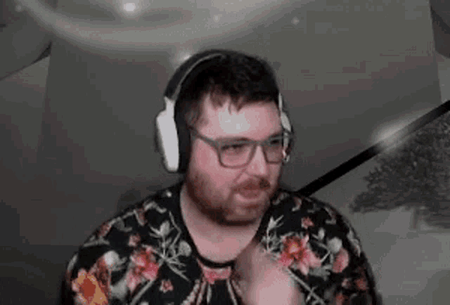 a man with a beard and glasses is wearing headphones and a floral sweater .