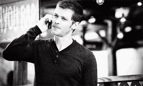 a man is standing in front of a building talking on a cell phone .