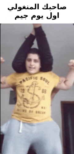a man wearing a yellow pacific soul shirt is holding another man 's legs