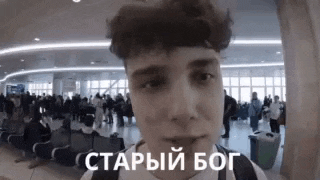 a young man is standing in an airport waiting area with a backpack .