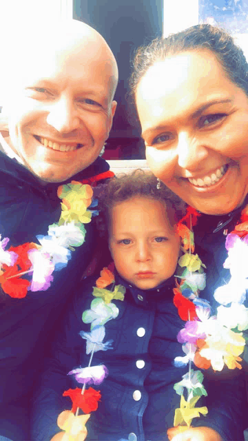 a man and a woman are posing for a picture with a little boy wearing a lei