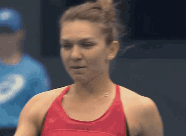 a woman wearing a red tank top with a necklace that says ' asics ' on it