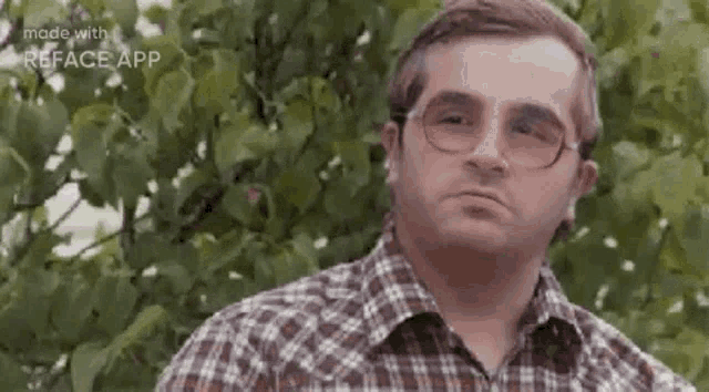 a man in a plaid shirt and glasses is making a funny face .