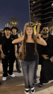 a girl in a black top is dancing with a group of men