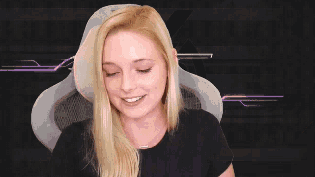 a woman in a black shirt is sitting in a white chair with the letter r on the back of it