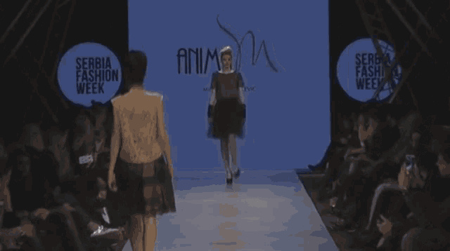 a woman walks down a runway at serbia fashion week