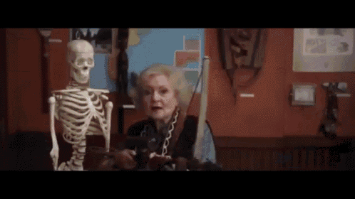 an elderly woman is sitting next to a skeleton