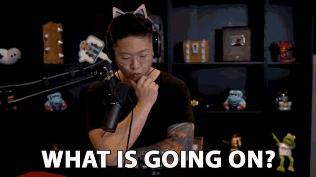 a man wearing headphones stands in front of a microphone and says what is going on ..