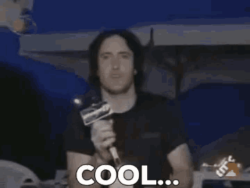 a man is talking into a microphone and the word cool is on the screen .