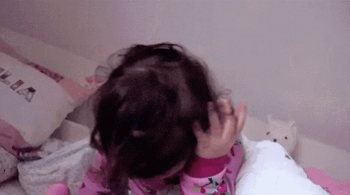 a little girl is laying on a bed with a stuffed animal in the background .