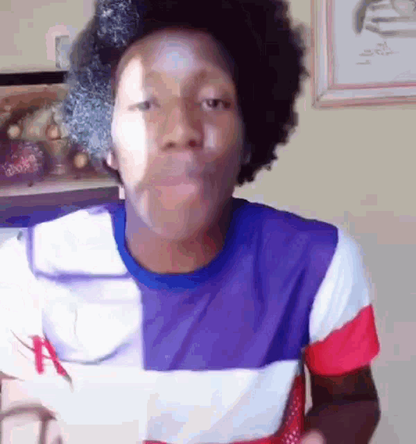 a man with a afro is wearing a striped shirt and making a funny face .