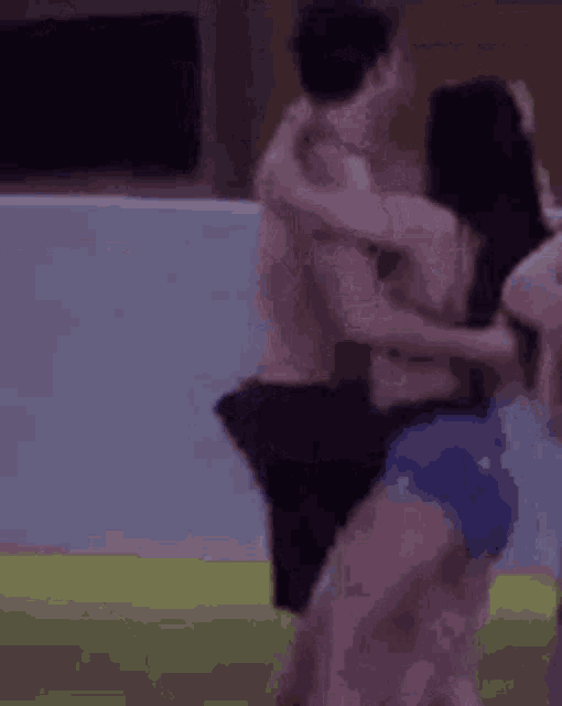a man without a shirt is holding a woman in his arms .