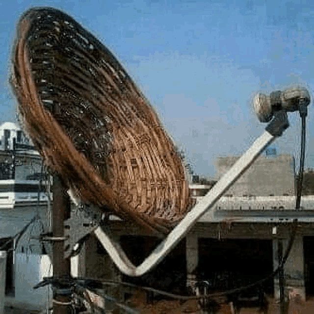 a satellite dish made out of a wicker basket is sitting on top of a pole .