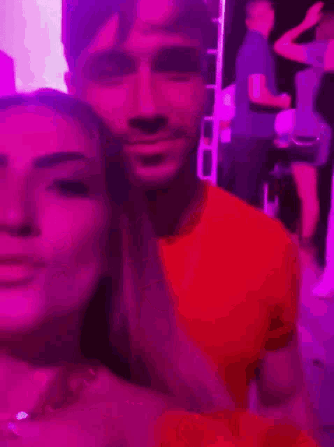 a man and a woman are standing next to each other in a dark room with purple lights .