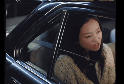 a woman is sitting in the back seat of a car looking out the window