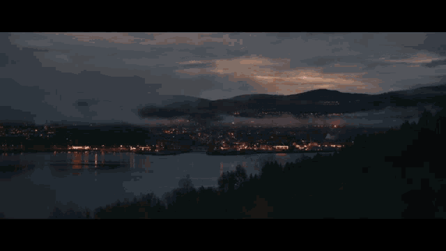 a lake surrounded by mountains and trees at night