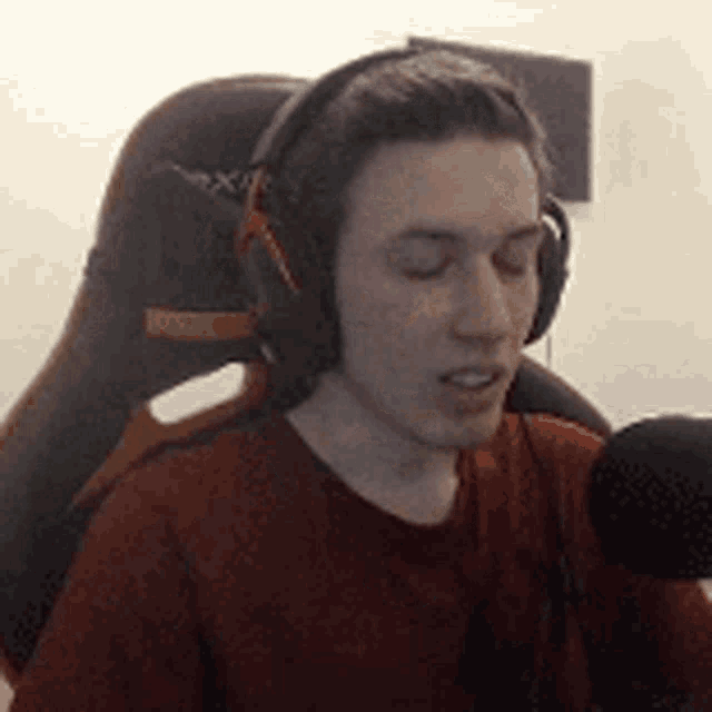 a young man wearing headphones and a red shirt is sitting in a chair .