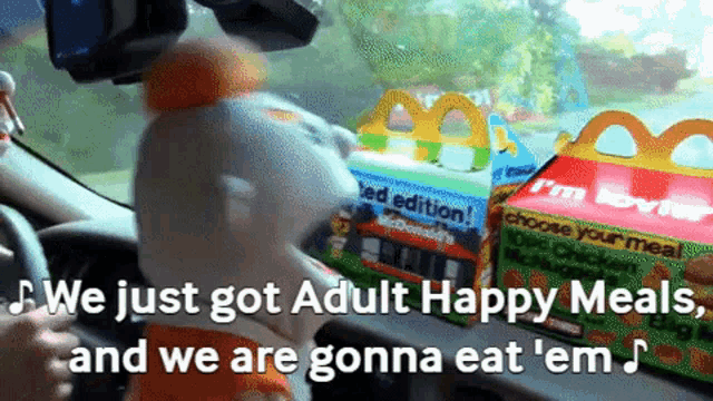 a person driving a car with a mcdonald 's happy meal in the back seat