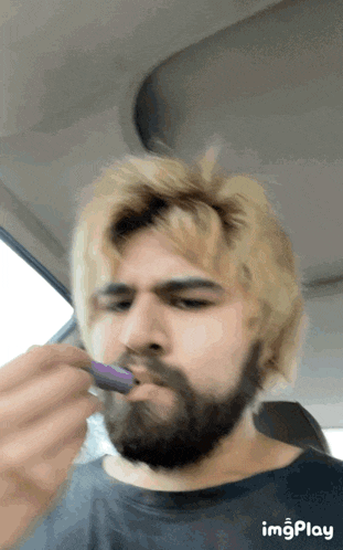 a man with blonde hair and a beard is brushing his teeth with a brush