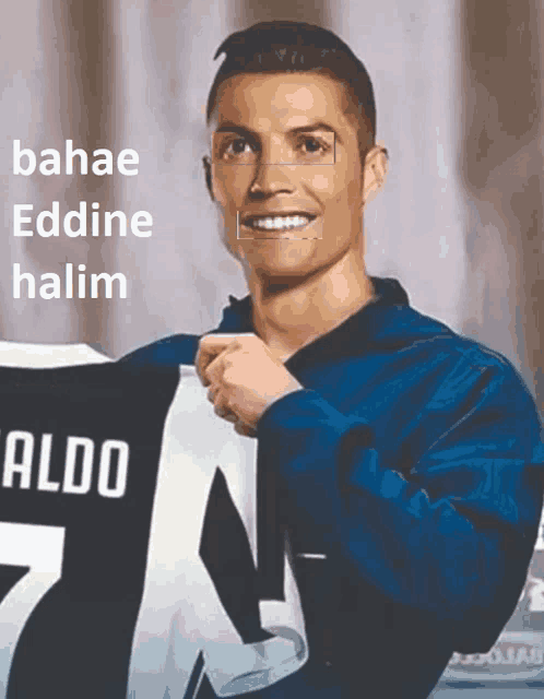 a man in a blue jacket is holding a jersey with the name aldo on it