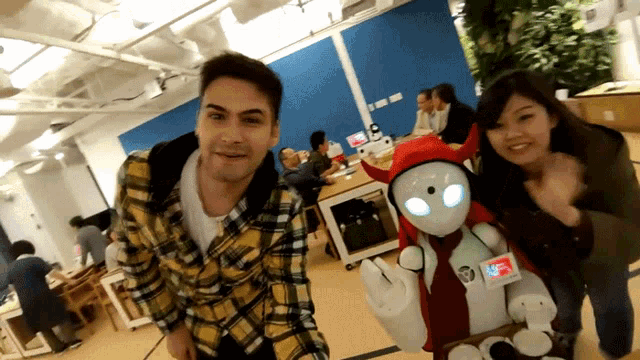 a man in a plaid shirt is standing next to a woman and a robot with a badge that says we