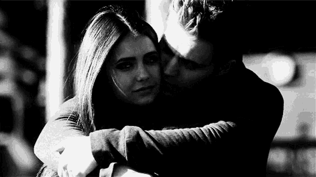 a man and woman are hugging each other in a black and white photo .