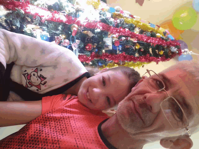a man and a little girl pose in front of a christmas tree