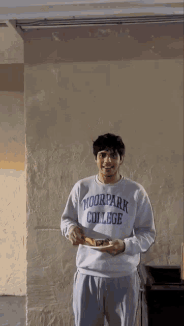 a man wearing a shirt that says park college is holding a plate of food