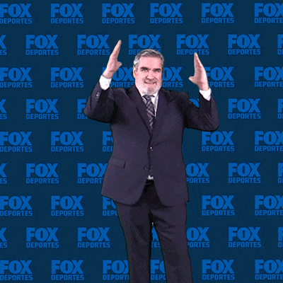 a man in a suit and tie stands in front of a fox deportes background