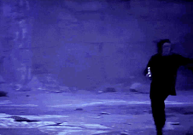 a man in a black jacket is running in a dark room with a blue background