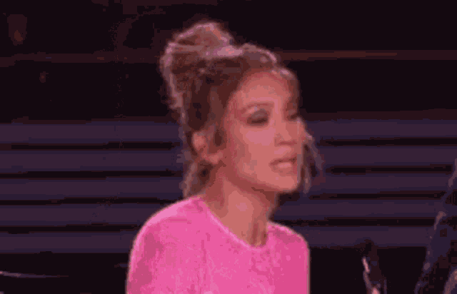 a woman in a pink dress is talking into a microphone .