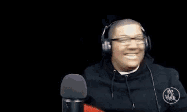 a man wearing glasses and headphones is holding a red object over his head .